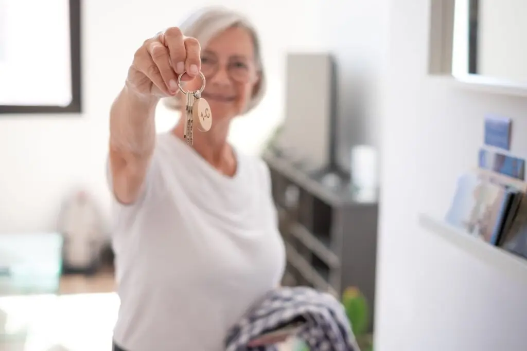 Older adult smiling and holding a key, symbolizing the question: is it time for senior living.