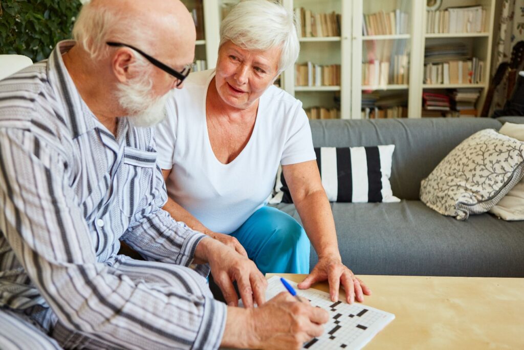 Two older adults work on a crossword puzzle together at home, a moment that captures the kind of connection and support that defines assisted living in Columbus, GA and helps families recognize the signs it's time for assisted living.